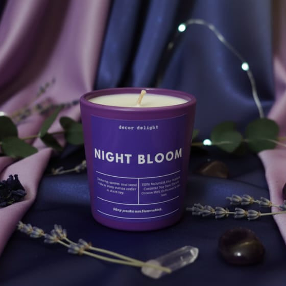 Purple candle labeled 'Night Bloom' on a decorative fabric background with flowers and leaves.